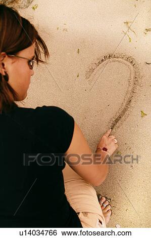Stock Photograph - Woman draws in the sand. Fotosearch