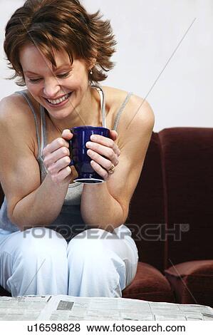 Stock Photo - Woman drinking coffee and reading newspaper. Fotosearch
