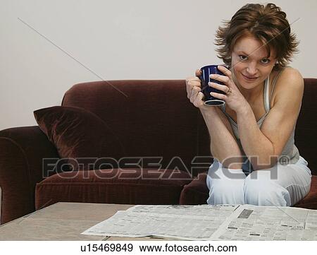 Stock Photo - Woman drinking coffee in front of newspaper. Fotosearch