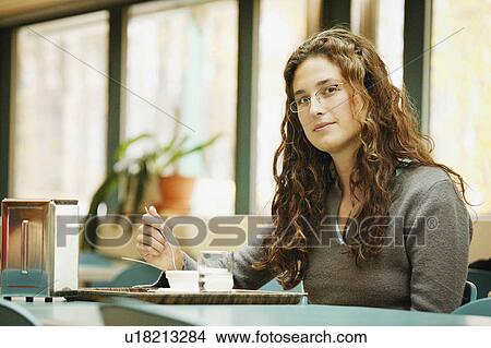 Picture - Woman eats in a cafeteria. Fotosearch
