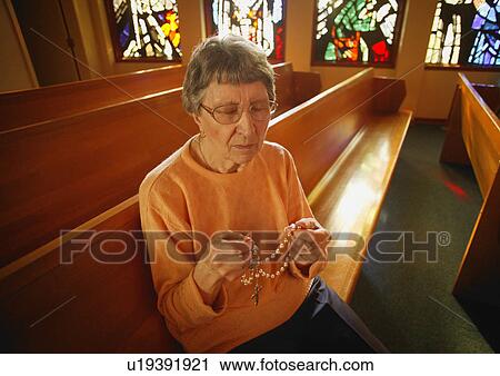Stock Image - Woman holding rosary beads. Fotosearch