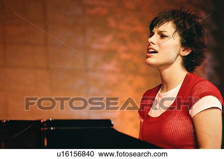 Stock Image - Woman plays the piano and sings. Fotosearch