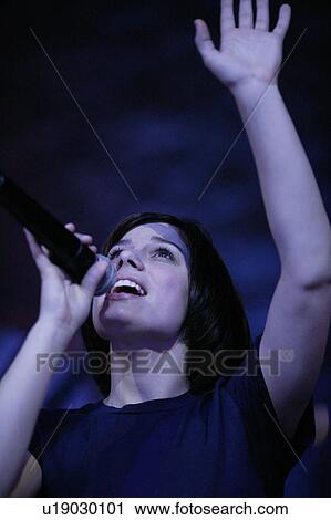 Stock Image - Woman raising hand in worship. Fotosearch