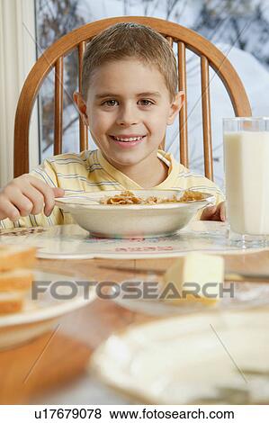 Young boy eating cereal at breakfast table View Large Photo Image Stock Photo - Young boy eating cereal at breakfast table. Fotosearch