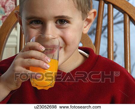 Stock Photo - Young boy smiling and drinking orange juice. Fotosearch