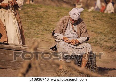 Stock Image - A fisherman mending his nets. Fotosearch