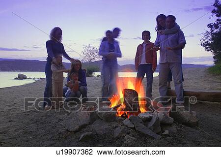 A group of friends and family around a bonfire on the beach View Large Photo Image Stock Image - A group of friends and family around a bonfire on the beach. Fotosearch
