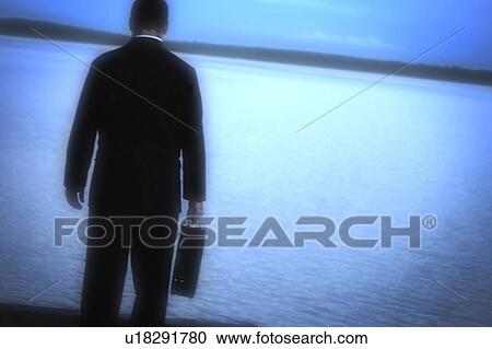 Stock Image - A man alone looking out over water. Fotosearch