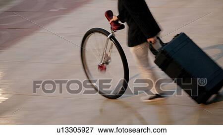 A person pushing a unicycle and pulling a suitcase View Large Photo Image Stock Photo - A person pushing a unicycle and pulling a suitcase. Fotosearch