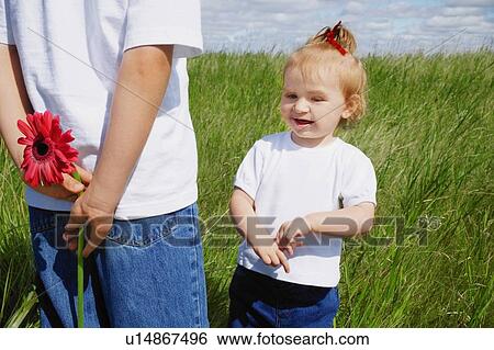 Stock Photograph - Boy holds a flower behind his back. Fotosearch