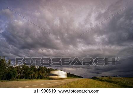 Dark clouds over vehicle on road View Large Photo Image Stock Photo - Dark clouds over vehicle on road. Fotosearch