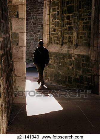 Man walking through old stone buildings View Large Photo Image Stock Image - Man walking through old stone buildings. Fotosearch