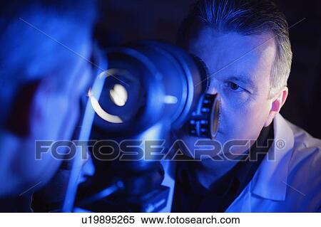 Optometrist administering an eye exam View Large Photo Image Stock Photography - Optometrist administering an eye exam. Fotosearch