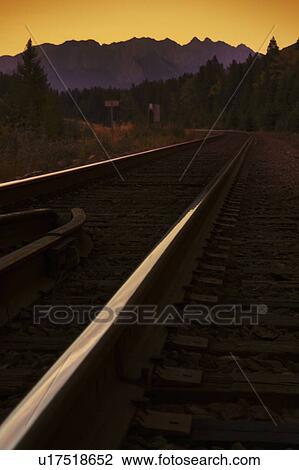 Stock Image - Railroad tracks through the mountains. Fotosearch