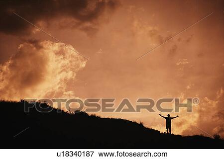 Silhouette of man standing with arms outstretched View Large Photo Image Stock Photo - Silhouette of man standing with arms outstretched. Fotosearch