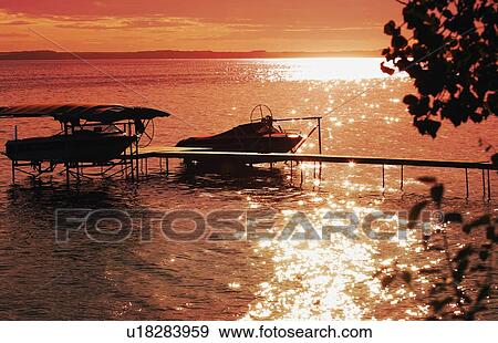Sunset over the lake and silhouette of boats View Large Photo Image Stock Photo - Sunset over the lake and silhouette of boats. Fotosearch