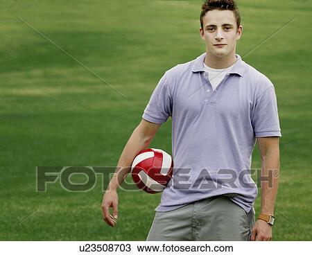 Stock Image - Young man holding a football. Fotosearch