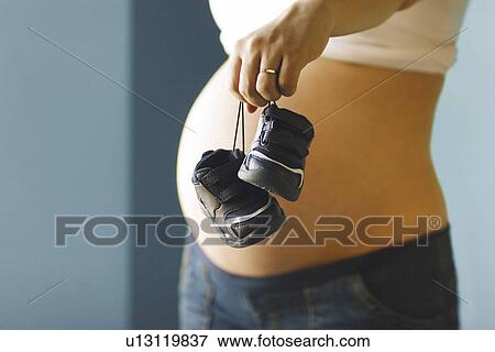 Expecting mother holding baby shoes View Large Photo Image Stock Photo - Expecting mother holding baby shoes. Fotosearch
