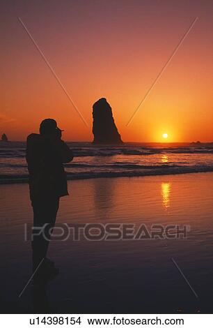 Silhouette of person viewing sunset, rock formation, Cannon Beach. View Large Photo Image Picture - Silhouette of person viewing sunset, rock formation, Cannon Beach.. Fotosearch