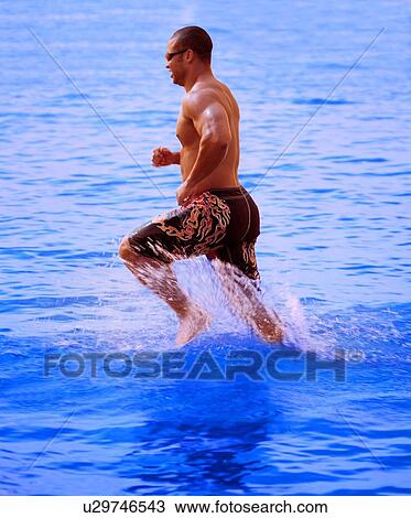 Stock Image - Man running in lake. Fotosearch