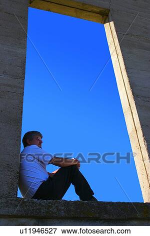 Man sitting on open ledge View Large Photo Image Stock Photo - Man sitting on open ledge. Fotosearch