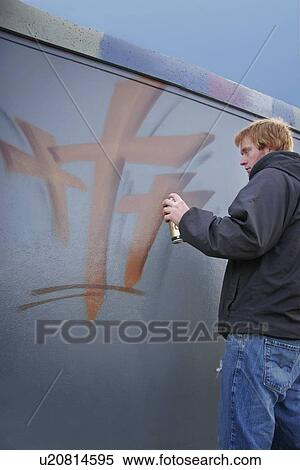 Stock Photography - Man spray paints on wall. Fotosearch