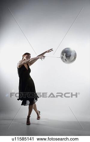 Stock Image - Woman dancing with disco ball. Fotosearch
