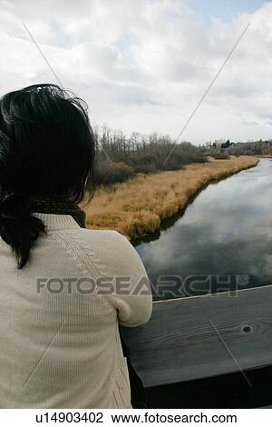 Stock Image - Woman looks out over a bridge. Fotosearch