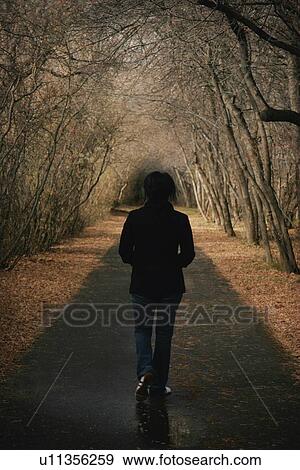 Stock Photo - Woman walks down a pathway. Fotosearch