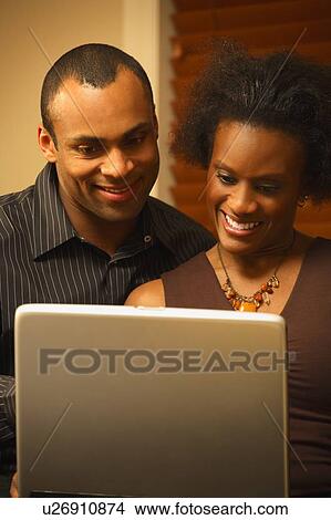 Picture - A couple views a laptop screen together. Fotosearch