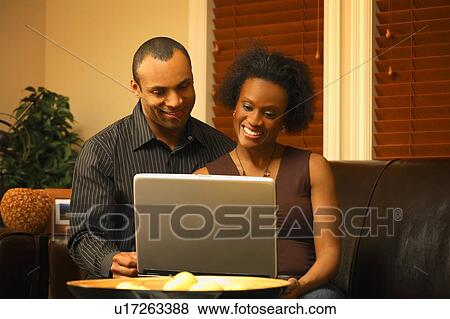 Stock Photo - A couple views a laptop together. Fotosearch