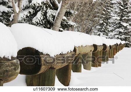 Stock Photo - Snow piled on log fence. Fotosearch