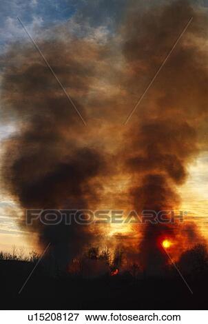 Stock Photo - Sunset behind columns of smoke. Fotosearch