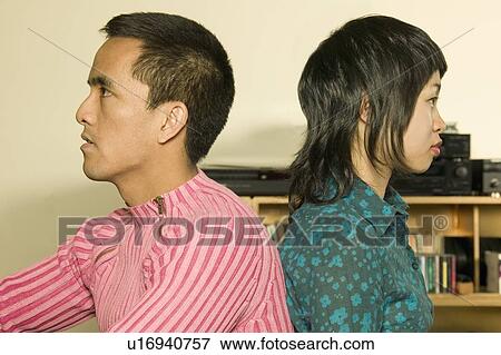 Stock Photo - Young couple with backs together. Fotosearch