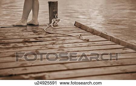 Stock Image - Child standing at the end of a pier. Fotosearch