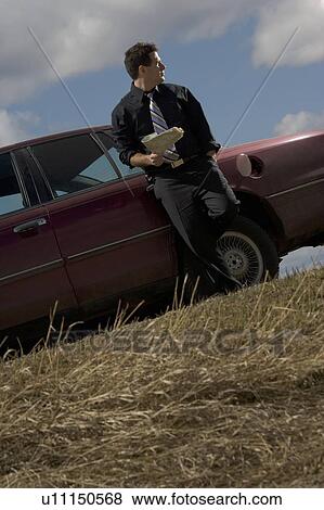 Stranded man standing by car View Large Photo Image Stock Photo - Stranded man standing by car. Fotosearch