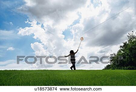 Picture - Woman in field with butterfly net. Fotosearch