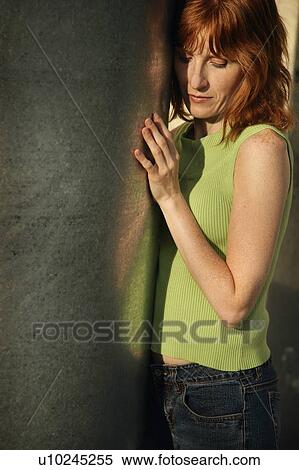 Stock Photography - Woman standing against wall. Fotosearch