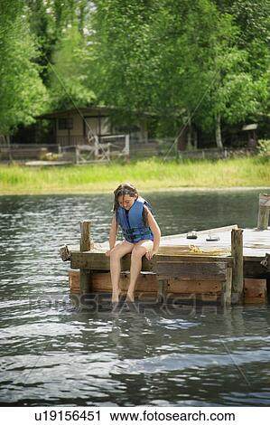 Stock Image - Young girl sitting on dock. Fotosearch