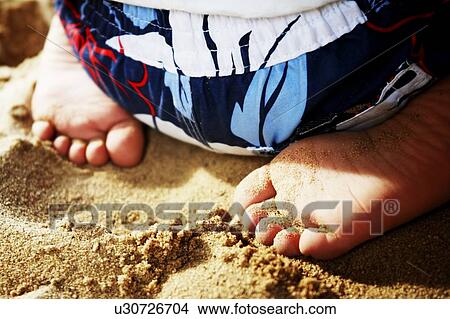 Picture - Child sitting in sand. Fotosearch