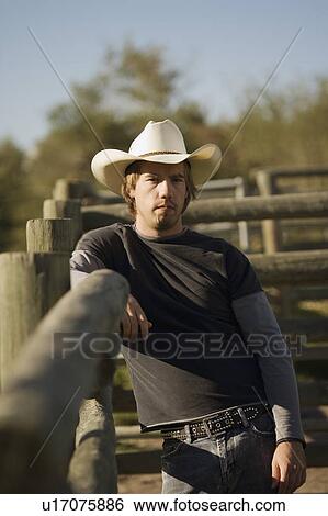 Cowboy standing by corral View Large Photo Image Stock Photograph - Cowboy standing by corral. Fotosearch