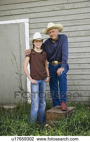 Stock Image - Grandfather and granddaughter wearing cowboy hats. Fotosearch