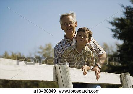 Stock Photo - Grandpa and grandson outside leaning on fence. Fotosearch