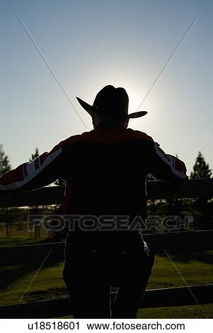 Stock Image - Rancher leaning on a corral. Fotosearch