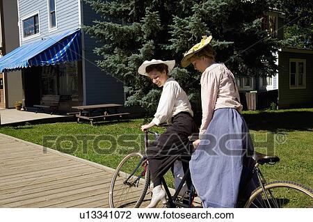 Stock Image - Women riding a tandem bicycle. Fotosearch
