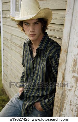 Stock Photography - Young man leaning against exterior of worn building. Fotosearch