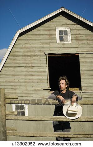 Stock Image - Young man leaning on fence. Fotosearch