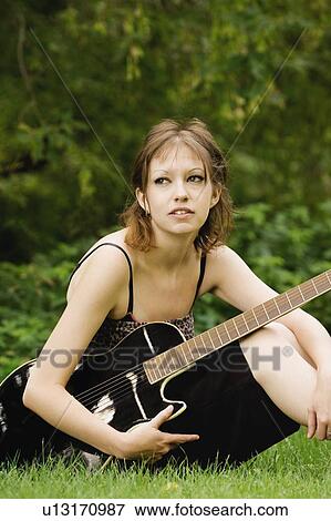 Young woman sitting outside with guitar View Large Photo Image Stock Photo - Young woman sitting outside with guitar. Fotosearch