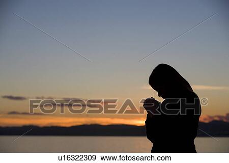 A girl prays at sunset View Large Photo Image Stock Photo - A girl prays at sunset. Fotosearch