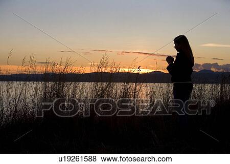 A teenage girl prays at sunset by the ocean. View Large Photo Image Stock Photo - A teenage girl prays at sunset by the ocean.. Fotosearch